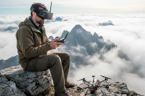 Drone cinematography in Mexico: FPV pilot with goggles on a mountain peak above the clouds, drone on the rock