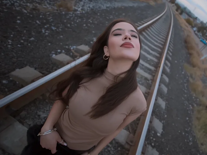 Social media video shot of a young woman on railroad tracks at dusk in Mexico