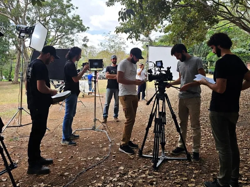 Equipo de filmación preparando cámara de cine, luces y monitores al aire libre bajo los árboles en México